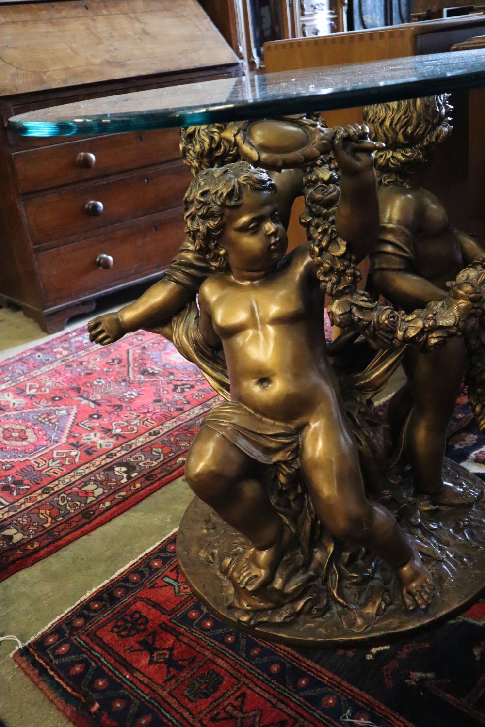 A cast gilt metal glass top cherub centre table, 81cm diameter